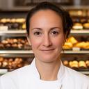 Portrait einer Confiserie-Inhaberin vor einer Vitrine mit Pralinen in Bern